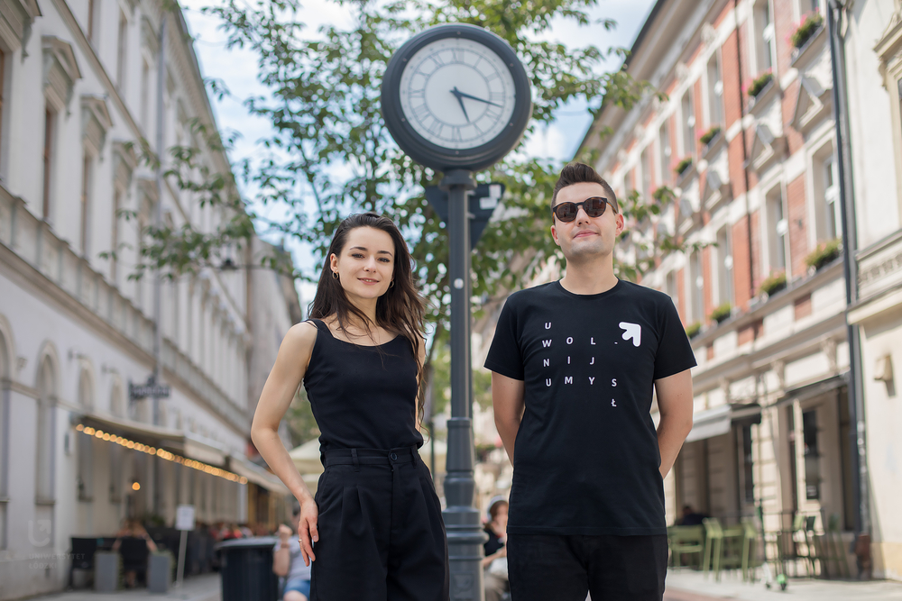 Dziewczyna i chłopak w czarnych koszulkach na tle ulicznego zegara