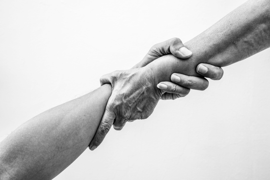 Help hands holding together in monochrome colour representing friendship, partnership, help and hope, donation and assistance