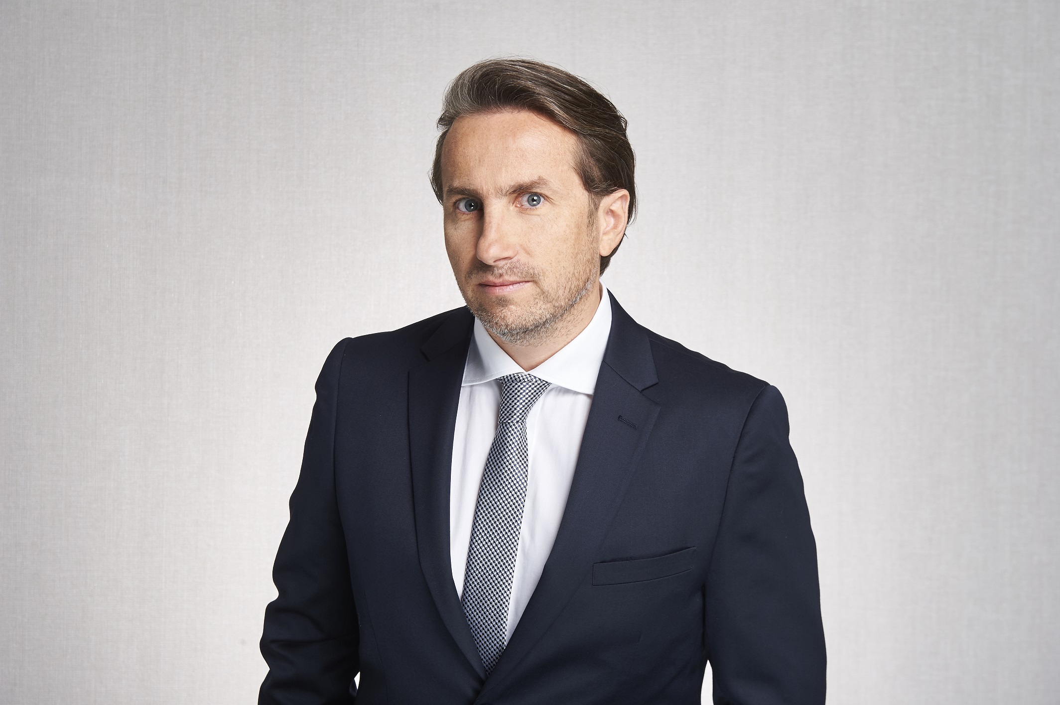 mężczyzna w ciemnej grafitowej marynarce pozuje do zdjęcia