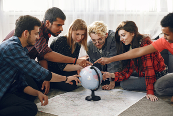 Grupa młodych osób dotyka globusa