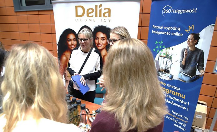 uczestnicy wydarzenia na stoisku na tle roll-upów firm