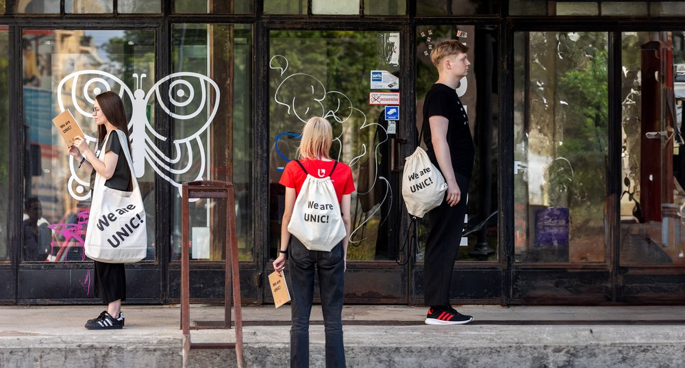  Three students standing on the stairs with bags and backpacks from the UNIC project