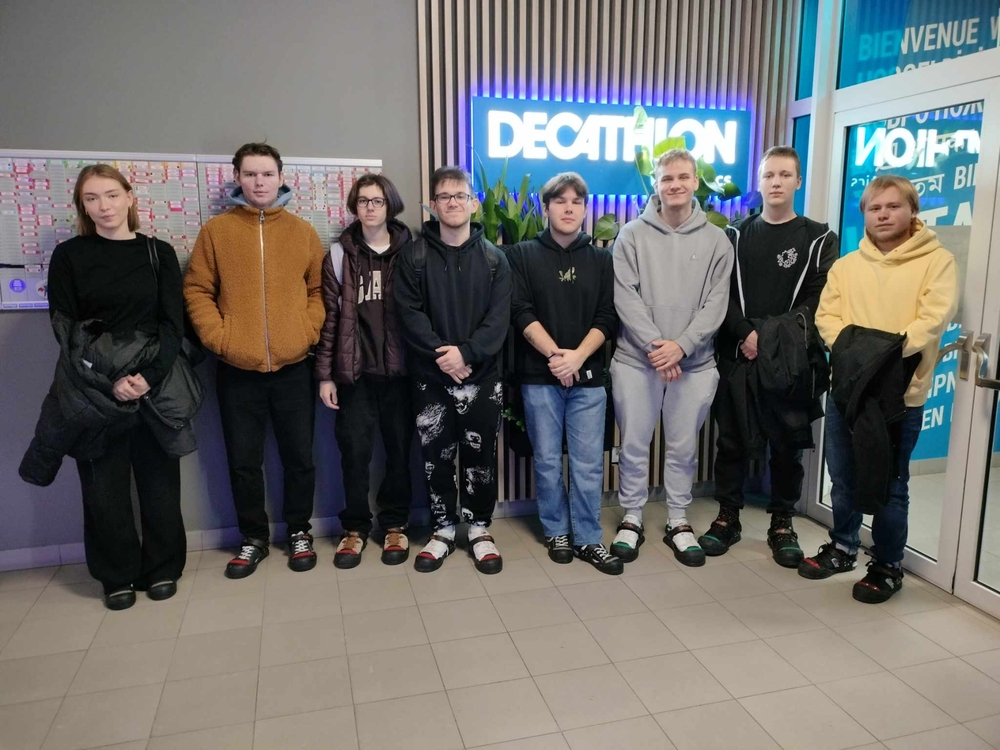 Grupa studentów stojąca pod logotypem firmy Decathlon