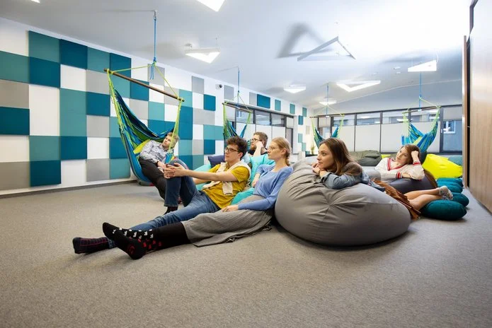 Zdjęcie wnętrza sali relaksu w CWiD UŁ. Na hamakach i pufach siedzą uśmiechnięci młodzi ludzie
