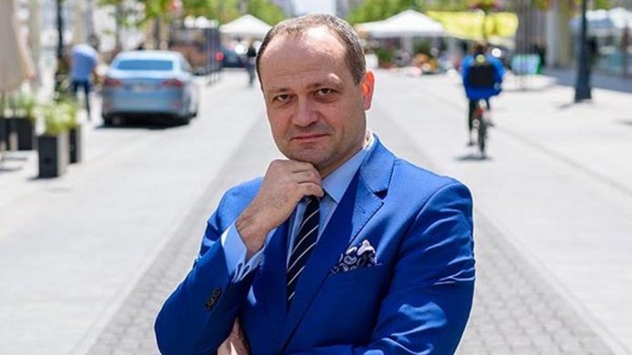 mężczyzna w niebieskim garniturze stoi na ulicy na deptaku