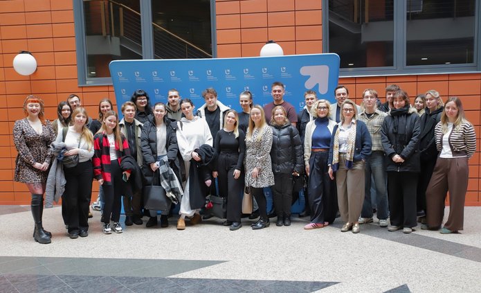 Grupa osób na tle ścianki Wydziału Zarządzania UŁ