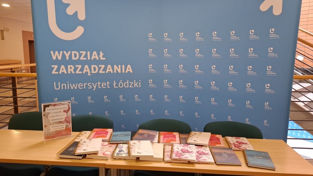 ścianka reklamowa Wydziału Zarządzania UŁ, stoły, rozłożone planery