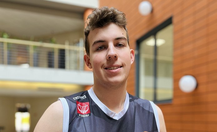 Zdjęcie przedstawia mężczyznę z piłką do koszykówki, stojącego na patio Wydziału