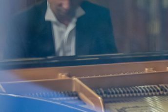 Mężczyzna w garniturze grający na fortepianie