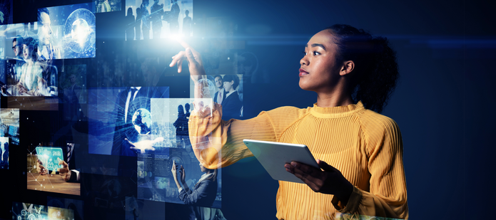 A young woman holding a tablet and pointing at images on a holographic screen