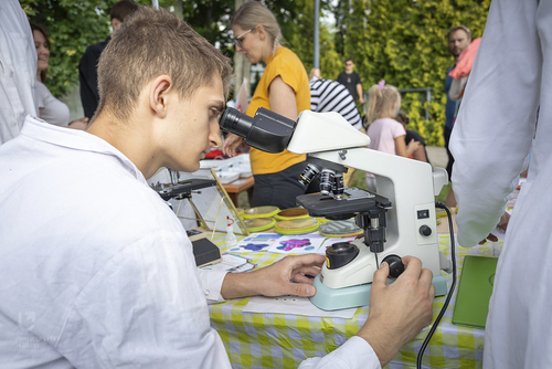 Student pochyla się nad okularem mikroskopu.