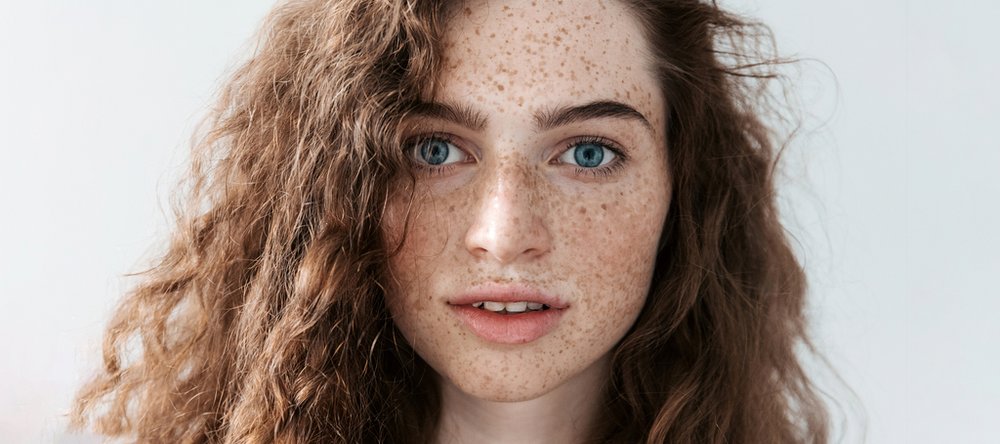 Twarz młodej kobiety o niebieskich oczach z kręconymi włosami