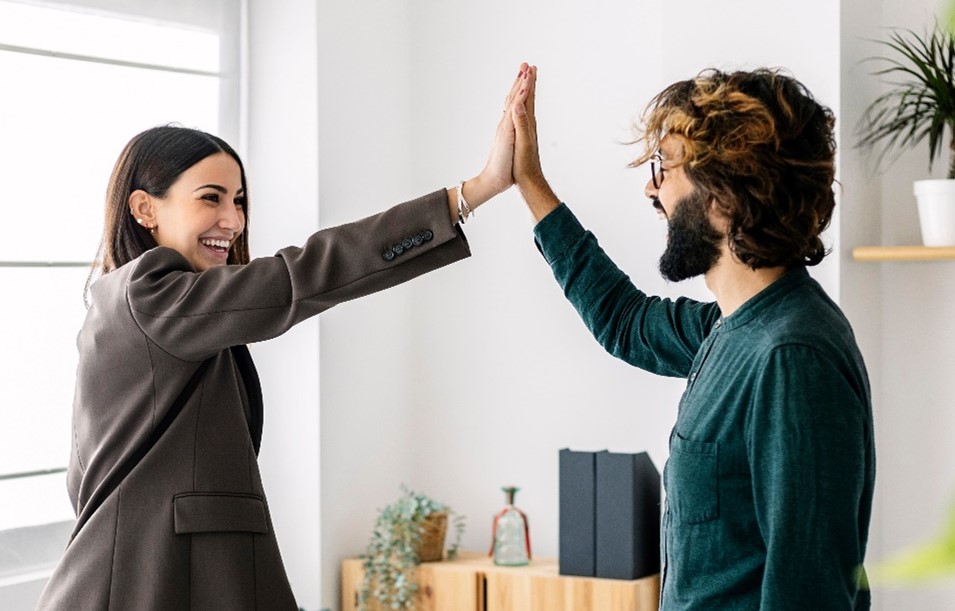 A smiling woman giving high-five to her happy friend